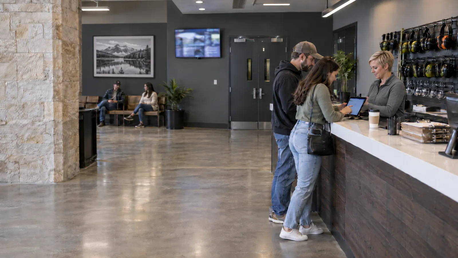 A couple signing in on a tablet at the check-in counter of a modern shooting range